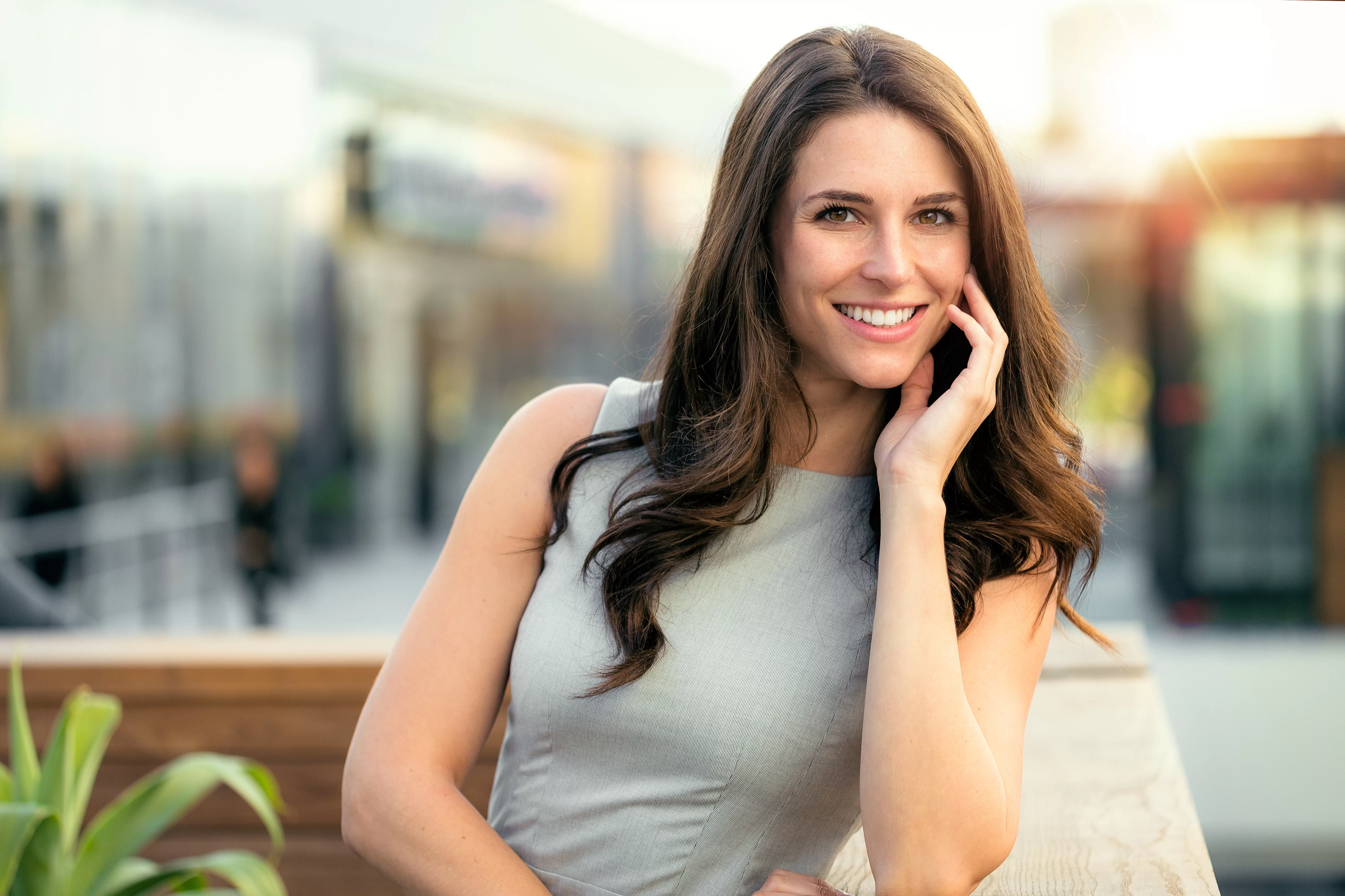 Woman sitting outside smiling with shops behind her blurred